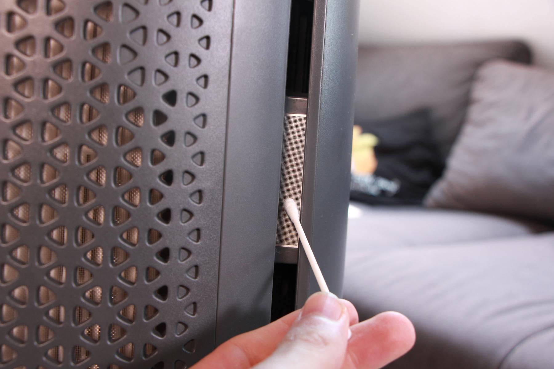 Der Lufteinlass von den Partikel-Sensoren des Philips Air Performer Series 8000 (AMF870/15) wird im Test mit einem trockenen Wattestäbchen gereinigt und von Staub befreit.